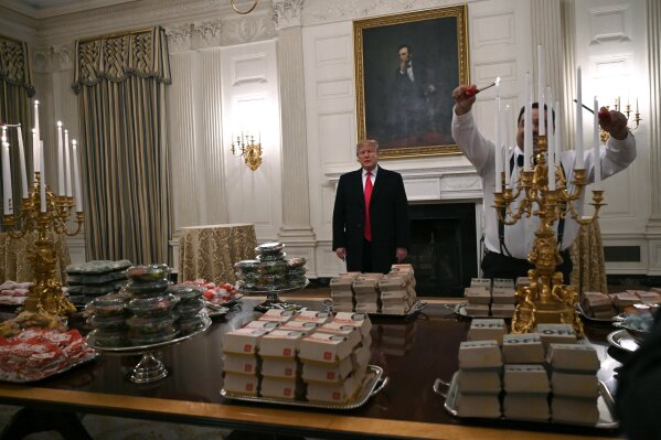 President Donald Trump talks to the press about the table full of fast food in the State Dining Room of the White House in Washington, Monday, Jan. 14, 2019, for the reception for the Clemson Tigers. (AP Photo/Susan Walsh)