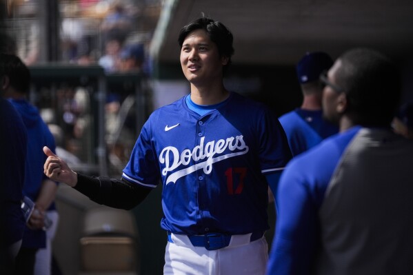 Los Angeles Dodgers designated hitter Shohei Ohtani walks in the dugout during the fourth inning of a spring training baseball game against the Chicago White Sox in Phoenix, Tuesday, Feb. 27, 2024. (AP Photo/Ashley Landis)