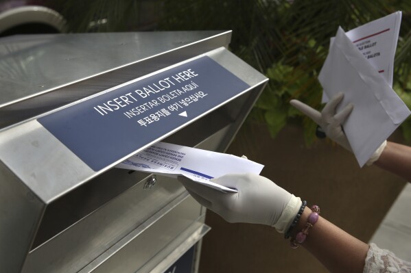 FILE - A woman wearing gloves drops off a mail-in ballot at a drop box in Hackensack, N.J., on July 7, 2020. A judge in Atlantic City, N.J. will hear arguments Friday, June 7, 2024, about whether to count about 1,900 mail ballots cast in one New Jersey county after election workers made a mistake handling them and members of the local elections board deadlocked on how to proceed. The case could determine the outcome of the Democratic primary in the race for the state's 2nd Congressional District. (AP Photo/Seth Wenig, File)