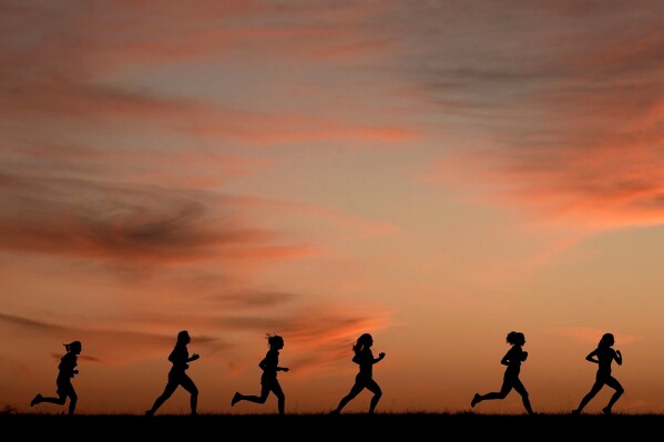 FILE - High school students run at sunset as they practice for the track and field season Monday, Feb. 28, 2022, in Shawnee, Kan. The killing of a 22-year-old nursing student has once again put the spotlight on dangers faced by female athletes who practice sports alone. (AP Photo/Charlie Riedel, File)
