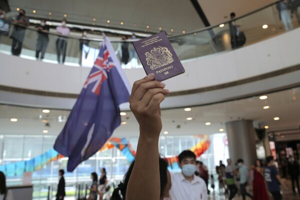 FILE - In this Friday, May 29, 2020 file photo, protesters hold a British National (Overseas) passport and Hong Kong colonial flag in a shopping mall during a protest against China's national security legislation for the city, in Hong Kong. Only five years ago, former British Prime Minister David Cameron was celebrating a “golden era” in U.K.-China relations, bonding with President Xi Jinping over a pint of beer at the pub and signing off trade deals worth billions. Those friendly scenes now seem like a distant memory, with hostile rhetoric ratcheting up this week over Beijing’s new national security law on Hong Kong. China has threatened “consequences” after Britain offered refuge to millions in the former colony. (AP Photo/Kin Cheung, file)