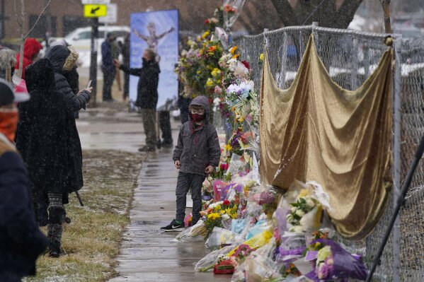Mourners leave bouquets on a fence put up around the parking lot where a mass shooting took place the day before in a King Soopers grocery store Tuesday, March 23, 2021, in Boulder, Colo. (AP Photo/David Zalubowski)