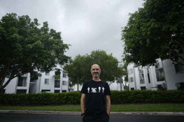 Web designer Joey Di Girolamo, 50, poses for a picture outside his apartment building, Thursday, July 20, 2023, in Pembroke Pines., Fla. Di Girolamo, who has worked from home since the pandemic, had to downsize from a two-bedroom to one-bedroom apartment, due to rent increases. (AP Photo/Rebecca Blackwell)
