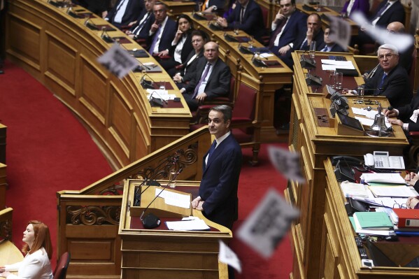 Protesters throw flyers as Greece's Prime Minister Kyriakos Mitsotakis speaks ON censure motion debate against the conservative government in parliament over a deadly rail disaster nearly two years ago, in Athens, Greece, Friday, March 7, 2025. Greece's conservative government has announced a major cabinet reshuffle on Friday, March 14, 2025 following declining approval ratings linked to the deadly 2023 rail disaster. (Ismini Vlassopoulou/InTime News via AP, File).