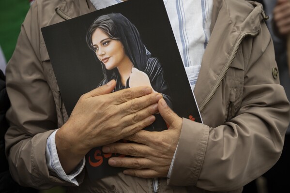 FILE - A portrait of Mahsa Amini is held during a rally calling for regime change in Iran following the death of Amini, a young woman who died after being arrested in Tehran by Iran's notorious 