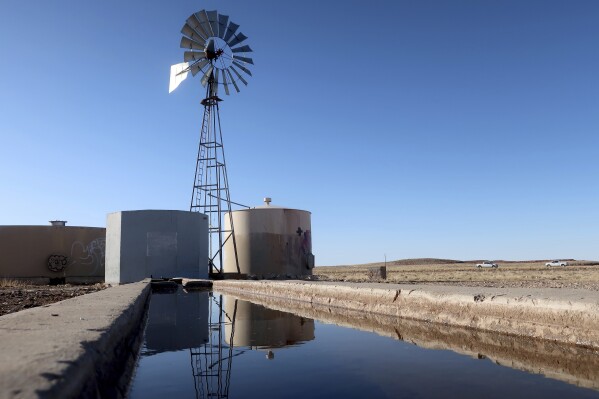A windmill draws water for livestock in Leupp, Ariz., on the Navajo Nation, Saturday, March 9, 2024. A proposed water rights settlement for three Native American tribes that carries a price tag larger than any such agreement enacted by Congress took a significant step forward late Monday, May 13, with introduction in the Navajo Nation Council. (AP Photo/Felicia Fonseca)
