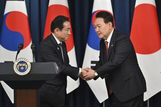 FILE - South Korean President Yoon Suk Yeol, right, shakes hands with Japanese Prime Minister Fumio Kishida during a joint press conference after their meeting at the presidential office in Seoul on May 7, 2023. Japan’s chief government spokesperson said Tuesday, May 9 the two countries and the United States were negotiating an agreement on sharing real-time data on North Korean missile launches, as defense cooperation among the three nations becomes increasingly important. (Jung Yeon-je/Pool Photo via AP, File)