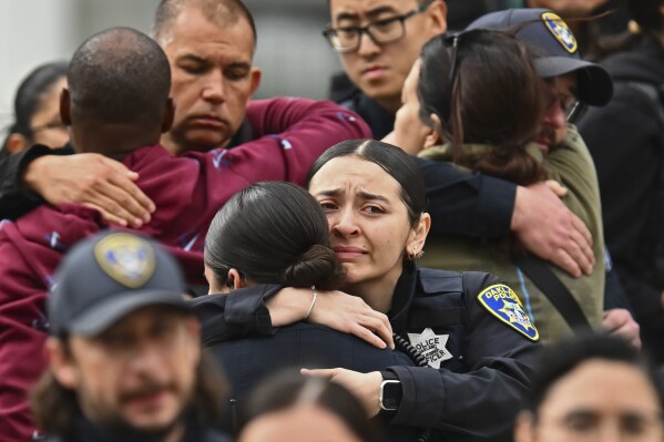 Oakland police officers console each other as they leave Highland Hospital in Oakland, Calif., on Friday, Dec. 29, 2023. An Oakland police officer was shot and killed Friday while answering a report of a burglary at a marijuana dispensary, authorities said. (Jose Carlos Fajardo/Bay Area News Group via AP)