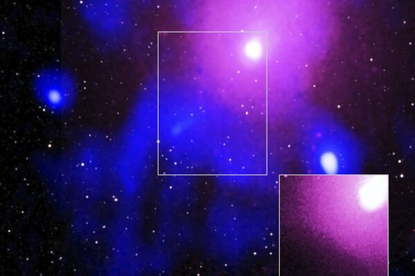 This image made available by NASA on Thursday, Feb. 27, 2020 shows the Ophiuchus galaxy cluster viewed in a composite of X-ray, radio and infrared data. The inset image at bottom right shows data from the Chandra X-ray Observatory which confirmed a cavity formed by a record-breaking explosion from a super-massive black hole. The explosion was so large it carved out a crater in the hot gas that could hold 15 Milky Ways, said lead author Simona Giacintucci of the Naval Research Laboratory in Washington. (Chandra: NASA/CXC/NRL/S. Giacintucci, et al., XMM: ESA/XMM; Radio: NCRA/TIFR/GMRT; Infrared: 2MASS/UMass/IPAC-Caltech/NASA/NSF via AP)