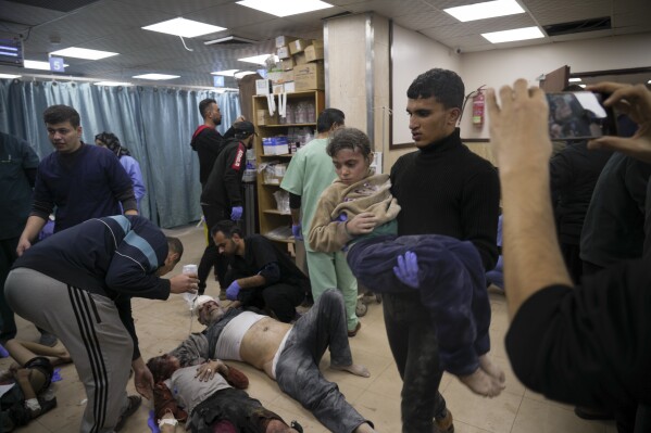 Palestinians wounded in Israeli bombardment are helped in a hospital in Deir al Balah, Monday, Jan. 1, 2024. (AP Photo/Hatem Moussa)