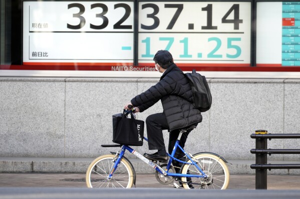 A person on a bicycle looks at an electronic stock board showing Japan's Nikkei 225 index at a securities firm Wednesday, Nov. 29, 2023, in Tokyo. (AP Photo/Eugene Hoshiko)