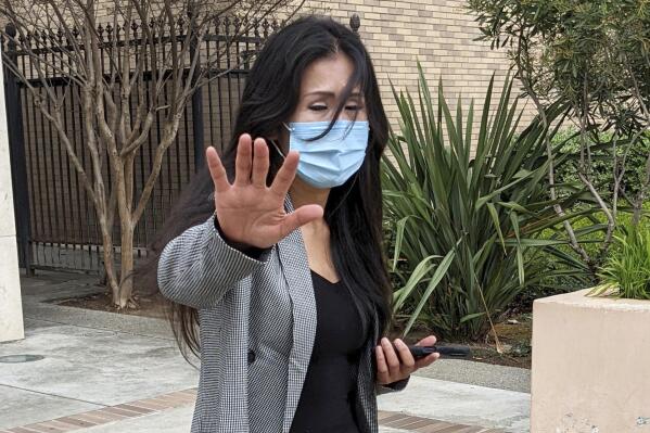 Julie Lee Choi waves off reporters outside Santa Clara Superior Court in San Jose, Calif., on Tuesday, March 29, 2022.  Choi, accused of harassing Apple CEO Tim Cook with pleas for sex and other crude suggestions before showing up at his Silicon Valley home last autumn and suggesting she could become violent agreed to stay way from him for the next three years under an agreement approved Tuesday. (AP Photo/Michael Liedtke)