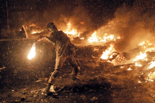 FILE - In this Jan. 22, 2014, file photo a protester throws a Molotov cocktail during clashes with police in central Kiev, Ukraine. On Nov. 21, 2023, Ukraine marks the 10th anniversary of the uprising that eventually led to the ouster of the country’s Moscow-friendly president. (AP Photo/Efrem Lukatsky, file)
