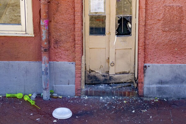 A damaged doorway is seen after members of the FBI and bomb squad detonated a suspicious package damaging the doorway according to an eyewitness on Bourbon Street during the investigation of truck crashing into pedestrians on Bourbon Street in the French Quarter in New Orleans, Wednesday, Jan. 1, 2025. The white lid of a blue cooler that the surveillance footage showed the suspect placing on Bourbon before the attack by Club 544 is below the doorway at Bourbon Street near Toulouse Street. (AP Photo/Matthew Hinton)