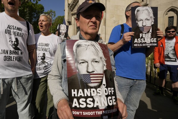 Protesters hold placards outside the High Court in London, Monday, May 20, 2024. WikiLeaks founder Julian Assange faces a hearing Monday in the High Court in London that could end with him being sent to the U.S. to face espionage charges, or provide him another chance to appeal his extradition. The outcome will depend on how much weight judges give to assurances U.S. officials have provided that Assange's rights won't be trampled if he goes on trial. (AP Photo/Kin Cheung)