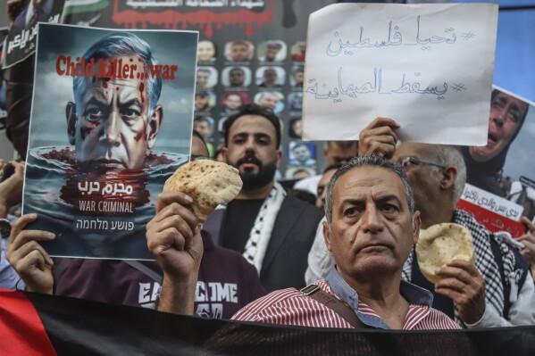 Egyptian activists hold bread as they participate in a pro-Palestinian protest outside the building of the Journalist Syndicate in Cairo, Egypt, Wednesday, April 3, 2024. Egyptian authorities arrested 10 activists who participated in the protest where they accused the government of contributing to the siege of Gaza and called for the expulsion of the Israeli ambassador, a human rights lawyer said. The Arabic reads: "long live Palestine, down with Zionists." (AP Photo/Mohamed El Raai)