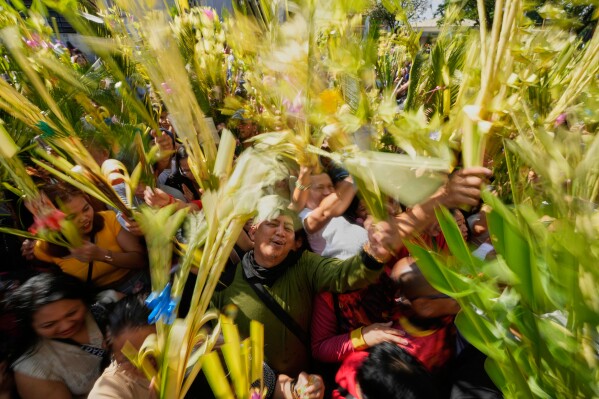 Devotees wave their palm fronds during blessing rites outside the Antipolo Cathedral in Antipolo city, Philippines as they observe Palm Sunday, April 13, 2025. (AP Photo/Aaron Favila)
