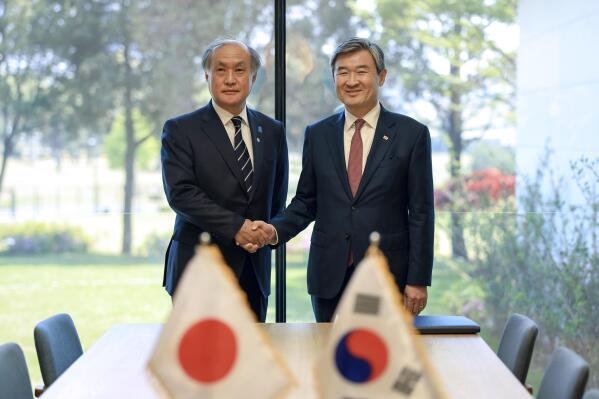 In this photo provided by South Korea Presidential Office, Takeo Akiba, left, Japan's National Security Adviser shakes hands with Cho Tae-yong, South Korean National Security Adviser, right, in Seoul, South Korea, Wednesday, May 3, 2023. (South Korea Presidential Office via AP)