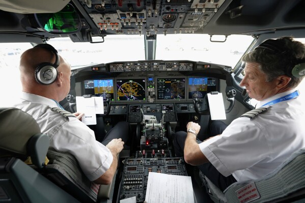 FILE - American Airlines pilot captain Pete Gamble, left, and first officer John Konstanzer conduct a pre-flight check in the cockpit of a Boeing 737 Max jet before taking off from Dallas Fort Worth airport on Dec. 2, 2020, in Grapevine, Texas. U.S. officials said Wednesday, June 14, 2023, that they will require new airline planes built after mid-2025 to have a second barrier to make it harder for passengers to break into the cockpit when the main door is open. (AP Photo/LM Otero, File)