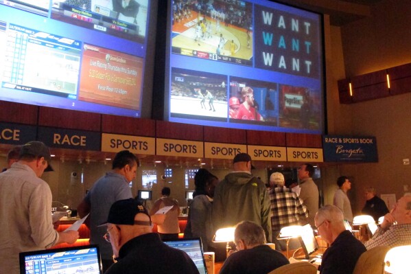 FILE - Gamblers line up to place bets on the NCAA men's college basketball tournament at the Borgata casino in Atlantic City N.J., March 21, 2019. When the NFL season kicks off, Kentucky residents will be able to legally bet on games for the first time. When they do, they also will be funding the state's first-ever program for people with gambling problems. (AP Photo/Wayne Parry, File)