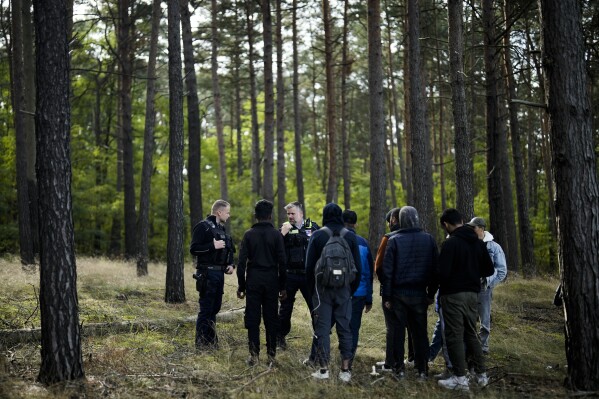 FILE - A Federal Police officer speaks into his radio as he and a colleague track down a group of migrants who have illegally crossed the border from Poland into Germany, while on patrol in a forest near Forst south east of Berlin, Germany, on Oct. 11, 2023. Chancellor Olaf Scholz is to meet Germany's 16 state governors on Monday Nov. 6, 2023 to address ways to deal with large numbers of migrants, an issue that has become a huge political problem for the government. (AP Photo/Markus Schreiber, File)