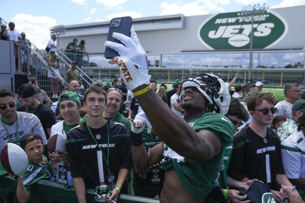 New York Jets' Will McDonald IV, front right, takes a photo with fans after a practice at the NFL football team's training facility in Florham Park, N.J., Sunday, July 30, 2023. (AP Photo/Seth Wenig)
