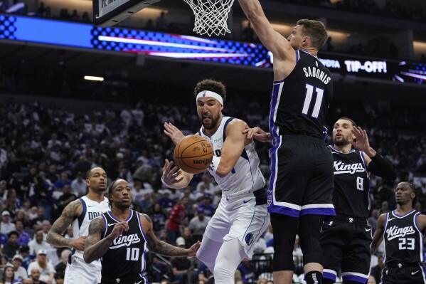 Dallas Mavericks guard Klay Thompson, center, passes the ball while defended by Sacramento Kings center Domantas Sabonis (11) during the first half of an NBA play-in tournament basketball game Wednesday, April 16, 2025, in Sacramento, Calif. (AP Photo/Godofredo A. Vásquez)