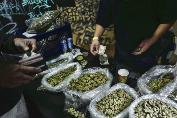 FILE - A vendor makes change for a marijuana customer at a cannabis marketplace in Los Angeles, April 15, 2019. (AP Photo/Richard Vogel, File)