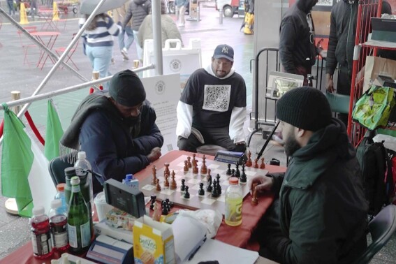 In this screen grab taken from video, Tunde Onakoya, 29- years old, a Nigerian chess champion and child education advocate, left, play a chess game in Times Square, New York, Thursday, April, 18, 2024.A Nigerian chess player and child education advocate is attempting to play chess nonstop for 58 hours in New York City's Times Square to break the global record for the longest chess marathon and raise $1m for the education of children across Africa. (AP Video/John Minchillo)