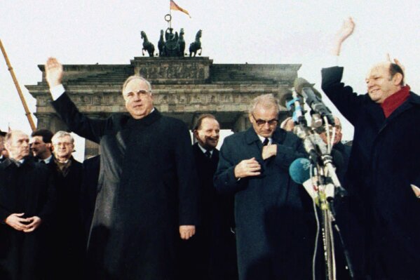 FILE - In this Dec. 22. 1989, file photo, West German chancellor Helmut Kohl, left, waves as he stands together with then East German Prime Minister Hans Modrow, second right, in front of the Brandenburg Gate during the opening ceremony of the Berlin Wall, Dec. 22. 1989. The abrupt fall of the Wall in 1989 and lightning speed that reunification took place took everyone by surprise at the time and was a shock to the system for some 16 million East Germans. Unrealistic expectations combined with other factors have helped lead to today’s discontent, providing fertile ground for the far-right. (AP Photo/File)