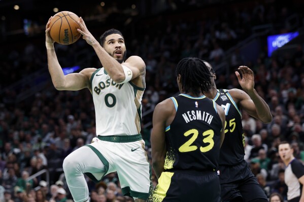 Boston Celtics' Jayson Tatum (0) shoots against Indiana Pacers' Aaron Nesmith (23) and Jalen Smith (25) during the first half of an NBA basketball game, Tuesday, Jan. 30, 2024, in Boston. (AP Photo/Michael Dwyer)
