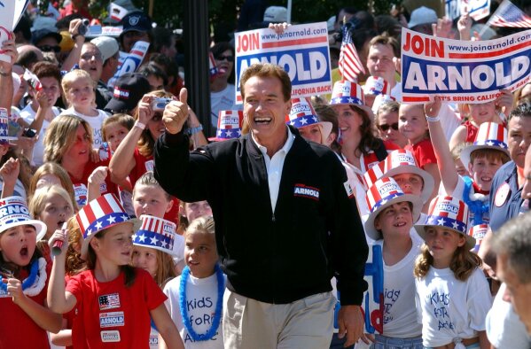 FILE - In this Oct. 5, 2003, file photo, Republican candidate for California governor Arnold Schwarzenegger walks up the steps to the state Capitol surrounded by children and waving to supporters during a campaign rally in Sacramento, Calif. California Gov. Gavin Newsom is facing a possible recall election as the nation's most populous state struggles to emerge from the coronavirus crisis. The prospect of the election is reviving memories of California's circus-like 2003 recall, in which voters installed Schwarzenegger as governor after deposing the unpopular Democrat Gray Davis. (AP Photo/Steve Yeater, File)