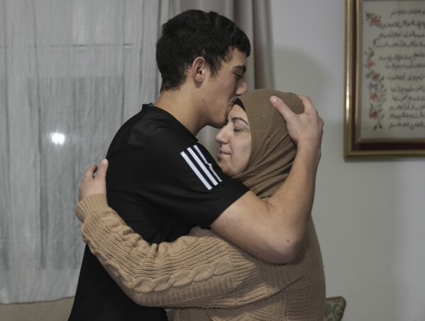 Released Palestinian prisoner Muhammad Abu al-Humus, 17, hugs his mother after arriving home in the Issawiya neighborhood of East Jerusalem on Tuesday, Nov. 28, 2023.  (AP Photo/Mahmoud Ilian)