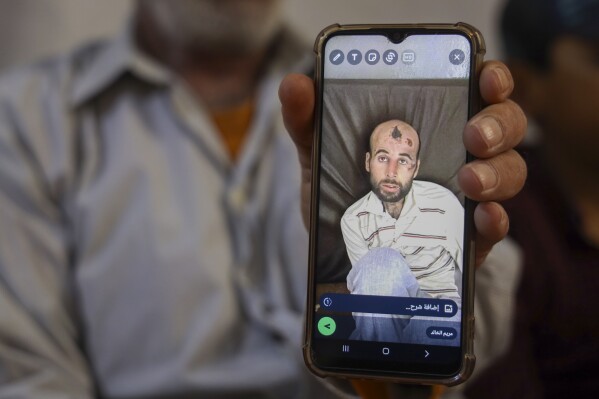 Walid Mohammed Abdel Bakki shows a picture of his dead son, Ali, on his mobile phone, in Idlib, Syria, Monday, May 27, 2024. After Ali's death in Lebanon, Bakki paid a smuggler $1,200 to take him and his 11-year-old son back to northwestern Syria, a journey that included an arduous trek through the mountains on foot. (AP Photo/Omar Albam)