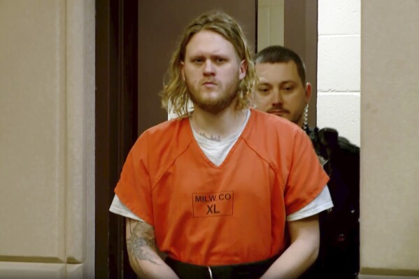 In this image taken from video, Maxwell Anderson is led into the courtroom for his initial appearance, Friday, April 12, 2024, in Milwaukee. Anderson 33, was charged Friday in the slaying of a woman whose dismembered leg was found near a beach down a bluff along Lake Michigan near Milwaukee. (WDJT-TV via AP)