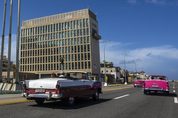 FILE - Tourists ride classic convertible cars on the Malecon beside the United States Embassy in Havana, Cuba, Oct. 3, 2017. U.S. intelligence agencies cannot link a foreign adversary to any of the incidents associated with so-called “Havana syndrome,” the hundreds of cases of brain injuries and other symptoms reported by American personnel around the world. The findings released Wednesday by American intelligence officials cast doubt on the longstanding suspicions by many people who reported cases that Russia or another country may have been running a global campaign to harass or attack Americans using some form of directed energy. (AP Photo/Desmond Boylan, File)