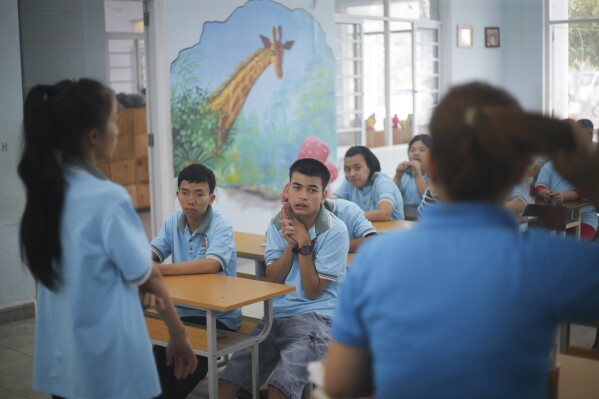 Truong Minh Phu, 20, centre, sits in a classroom with other students at a school for victims of Agent Orange in Da Nang, Vietnam, March 7, 2025. (AP Photo/Aniruddha Ghosal)