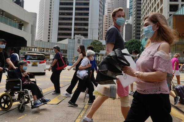 People wearing face masks to prevent the spread of coronavirus walk on a downtown street in Hong Kong, Tuesday, Aug. 17, 2021. Hong Kong will tighten entry restrictions for travelers arriving from the United States and 14 other countries from Friday, increasing the quarantine period to 21 days. (AP Photo/Vincent Yu)