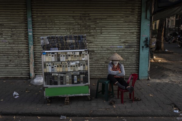 A vendor selling used remote controls for various home appliances takes a nap in Nhat Tao market, the largest informal recycling market in Ho Chi Minh City, Vietnam, Sunday, Jan. 28, 2024. (AP Photo/Jae C. Hong)