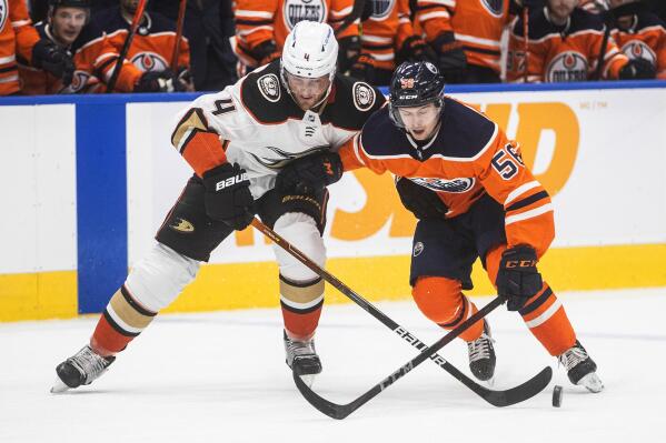 Anaheim Ducks' Cam Fowler (4) and Edmonton Oilers' Kailer Yamamoto (56) battle for the puck during the second period of an NHL hockey game Tuesday, Oct. 19, 2021, in Edmonton, Alberta. (Jason Franson/The Canadian Press via AP)