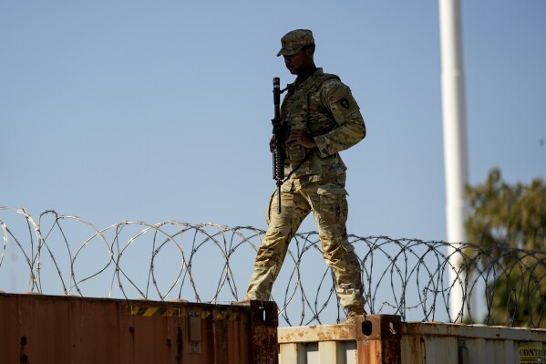 FILE - A guardsman walks over rail cars with Concertina wire along the Texas-Mexico border, Jan. 3, 2024, in Eagle Pass, Texas. Senate negotiators were trying to close on a bipartisan border security proposal Monday, Jan. 8, that could unlock Senate Republican support for Ukraine aid. But as Congress returns, House conservatives are trying to interject their own hardline immigration demands. (AP Photo/Eric Gay, File)
