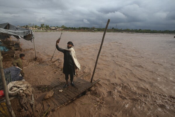 A man takes a selfie on the bank of a stream, which is overflowing following heavy rains, on the outskirts of Peshawar, Pakistan, Monday, April 15, 2024. Lightnings and heavy rains killed dozens of people, mostly farmers, across Pakistan in the past three days, officials said Monday, as authorities declared a state of emergency in the country's southwest following an overnight rainfall to avoid any further casualties and damages. (AP Photo/Muhammad Sajjad)