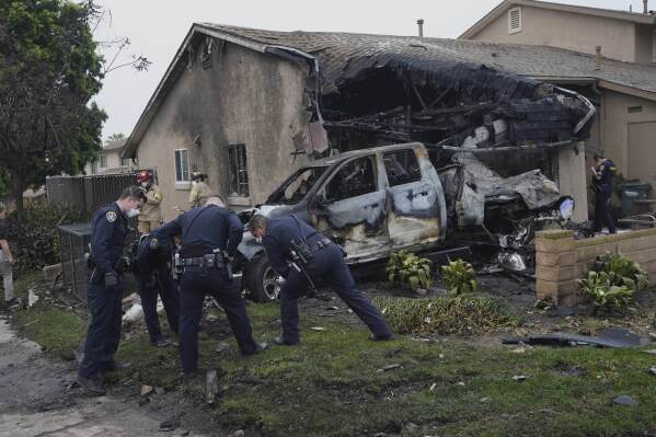 Authorities work the scene where a small plane crashed into a San Diego neighborhood, setting several homes on fire and forcing evacuations along several blocks early Thursday, May 22, 2025. (AP Photo/Gregory Bull)