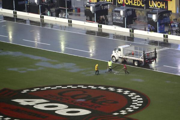 Track workers attempt to clear some of the water off of the infield grass as rain falls before a NASCAR Cup Series auto race at Daytona International Speedway, Saturday, Aug. 27, 2022, in Daytona Beach, Fla. (AP Photo/David Graham)