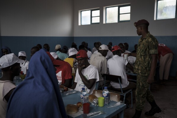 Atendidos por soldados y voluntarios de la Cruz Roja, los sobrevivientes del desafortunado viaje almuerzan en una escuela convertida en refugio, en la isla de Sal, Cabo Verde, el lunes 21 de agosto de 2023, una semana después de que su barco fuera encontrado perdido en el mar. (AP Foto/Felipe Dana)