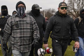 FILE - In this Jan. 6, 2021, file photo, Proud Boys members Joseph Biggs, left, and Ethan Nordean, right with megaphone, walk toward the U.S. Capitol in Washington. A federal judge has ordered Biggs and Nordean, two leaders of the far-right Proud Boys extremist group, to be arrested and jailed while awaiting trial on charges they planned and coordinated an attack on the U.S. Capitol to stop Congress from certifying President Joe Biden’s electoral victory. The two had been free since their March 10 indictment, but U.S. District Judge Timothy Kelly concluded April 19, that the two men are dangerous and won't abide by release conditions. (AP Photo/Carolyn Kaster, File)