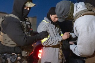 U.S. Immigration and Customs Enforcement officers use a chain to more comfortably restrain a detained person using handcuffs positioned in front, Jan. 27, 2025, in Silver Spring, Md. (AP Photo/Alex Brandon, file)