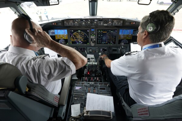 File - Pilots conduct a pre-flight check in the cockpit of a jet before taking off from Dallas Fort Worth airport in Grapevine, Texas, on Dec. 2, 2020. Aviation experts say the incident on Sunday in which an off-duty pilot, riding in a jump seat in a cockpit, tried to disable a jetliner in midflight renews questions about the threat posed by airline workers who have special access to places where passengers can't go. (AP Photo/LM Otero, File)