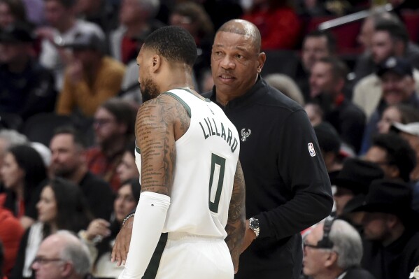 Milwaukee Bucks Head coach Doc Rivers, right, speaks with guard Damian Lillard (0) during the first half of an NBA basketball game against the Portland Trail Blazers in Portland, Ore., Wednesday, Jan. 31, 2024. (AP Photo/Steve Dykes)