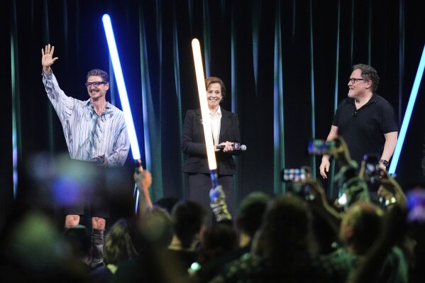 From left, actors Pedro Pascal and Sigourney Weaver react to audience members as director Jon Favreau looks on during a fan convention called the Star Wars Celebration Japan in Chiba, near Tokyo, Friday, April 18, 2025. (AP Photo/Hiro Komae)